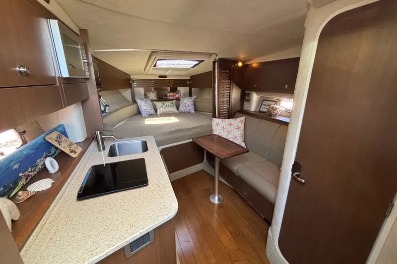 Slide: The Image of 2013 Sea Ray Sundancer 310 interior with kitchenette, seating, and cozy sleeping area. - 22