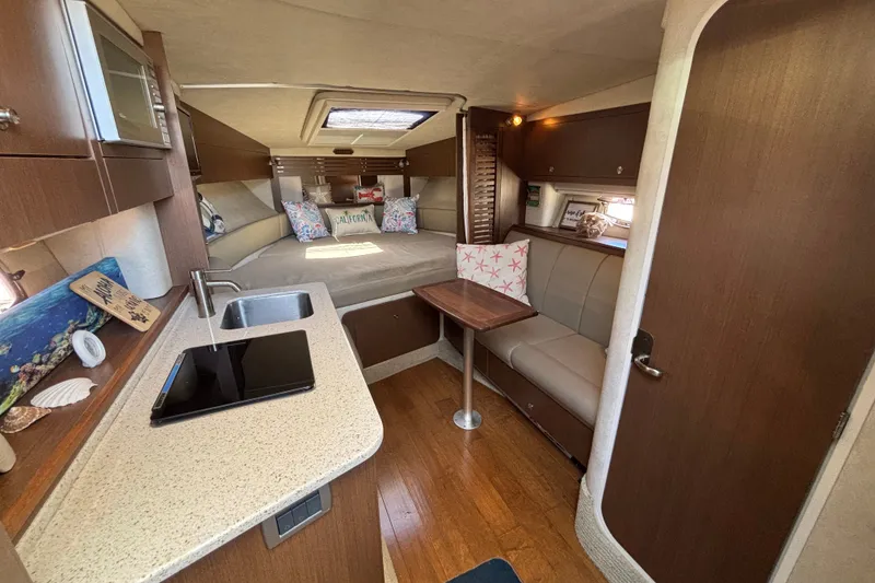 Slide: The Image of Interior of 2013 Sea Ray Sundancer 310, featuring cozy seating, kitchenette, and modern decor. - 23