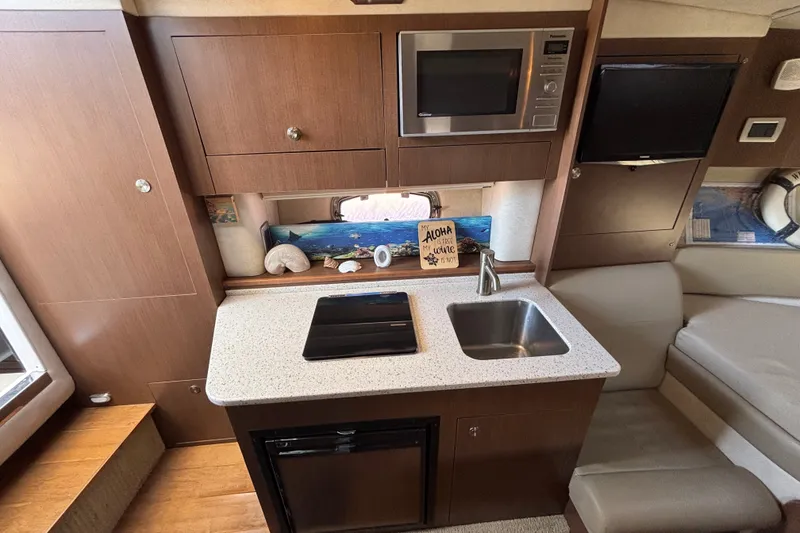 Slide: The Image of Interior of 2013 Sea Ray Sundancer 310 with kitchenette, microwave, and cozy seating area. - 24