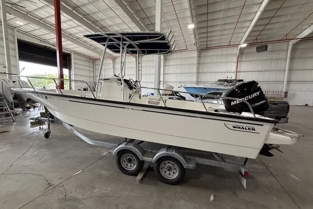 The Image of 2015 Boston Whaler 210 Montauk boat on trailer in warehouse setting. - 0