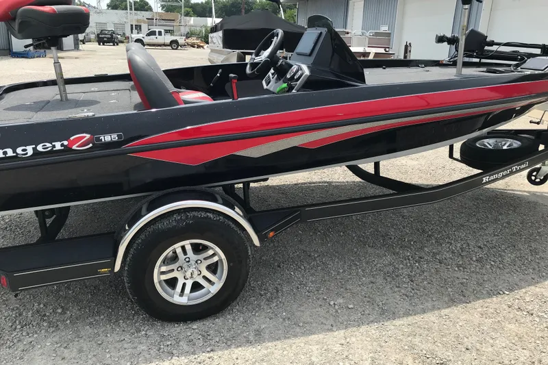 The Image of 2024 Ranger Z185 boat with red accents on a trailer in a parking area. - 2