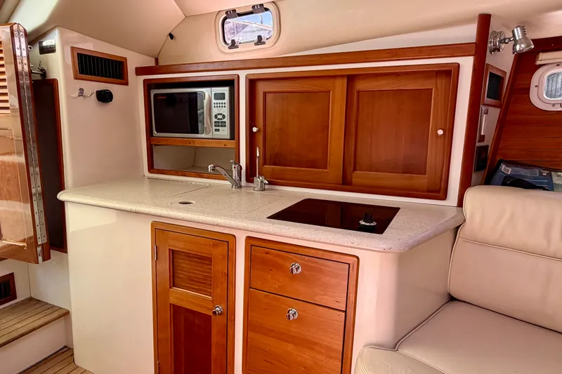 Slide: The Image of 2009 MJM 29z Downeast yacht interior with kitchenette, featuring wood cabinetry and modern appliances. - 20