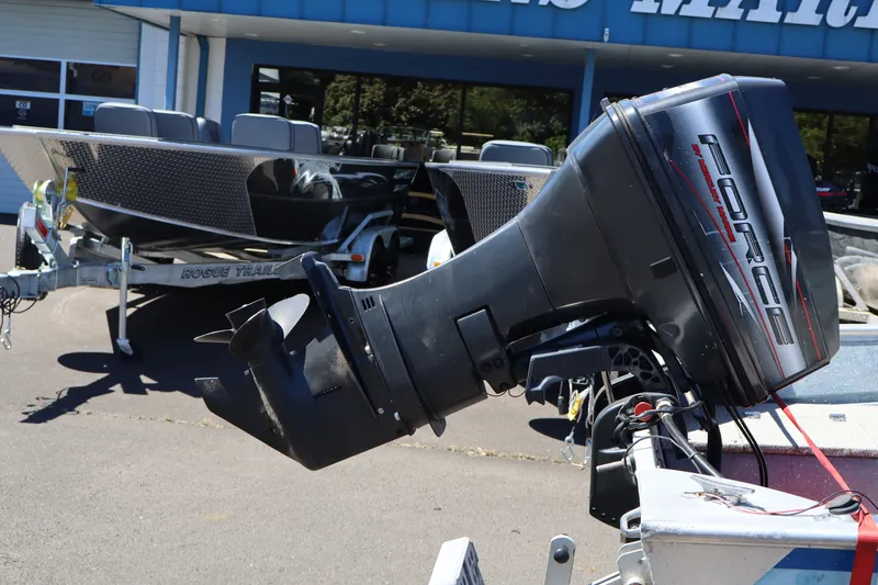 Slide: The Image of 1985 Klamath 15 boat with Force outboard motor, parked on a trailer outside a dealership. - 4