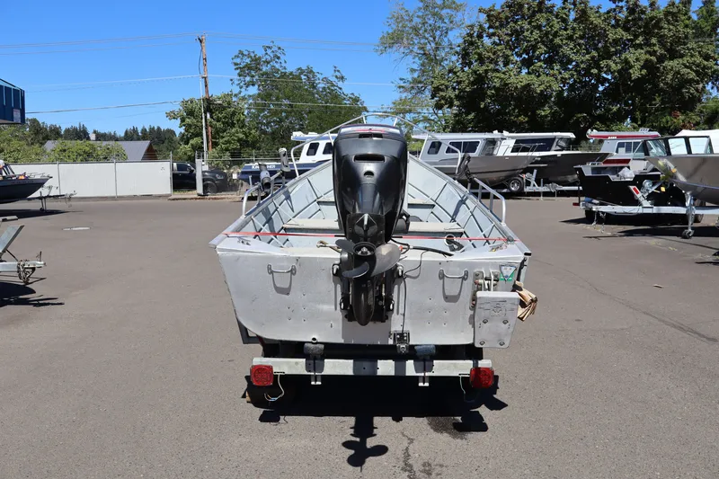 Slide: The Image of 1985 Klamath 15 boat with outboard motor in a parking lot. - 5
