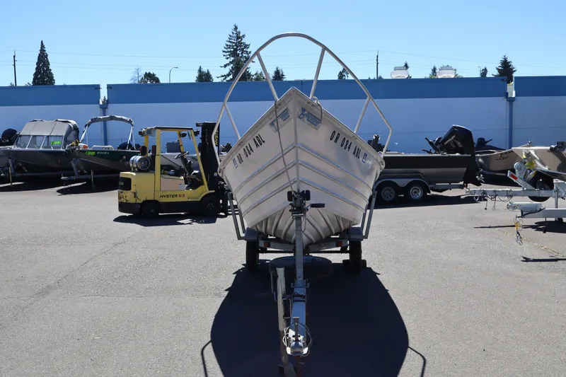 Slide: The Image of 1985 Klamath 15 boat on trailer in outdoor lot, surrounded by other boats and a forklift. - 3