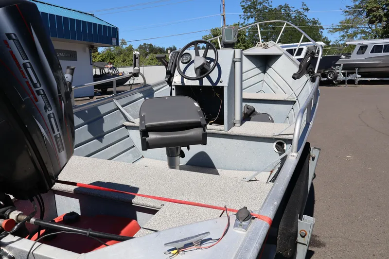 Slide: The Image of 1985 Klamath 15 boat with steering wheel and outboard motor in a parking lot. - 6