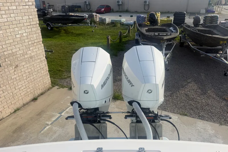 Slide: The Image of Twin Mercury outboard engines on a 2002 Silverhawk 240 Center Console boat, parked near trailers. - 16