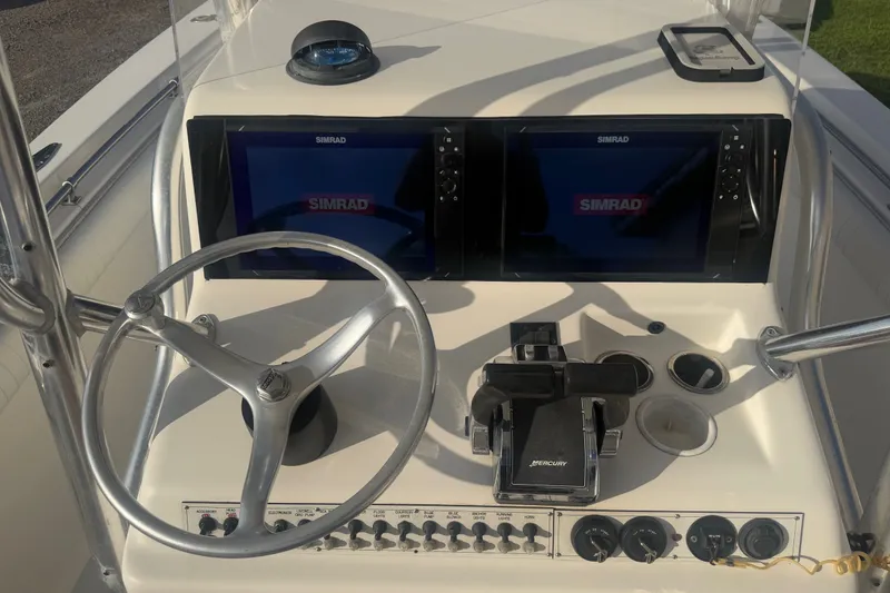 Slide: The Image of 2002 Silverhawk 240 Center Console boat dashboard with dual Simrad displays and steering wheel. - 12