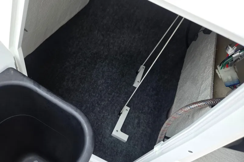 Slide: The Image of Interior storage compartment of 2023 Yamaha AR195 boat, featuring wiring and carpeted flooring. - 17