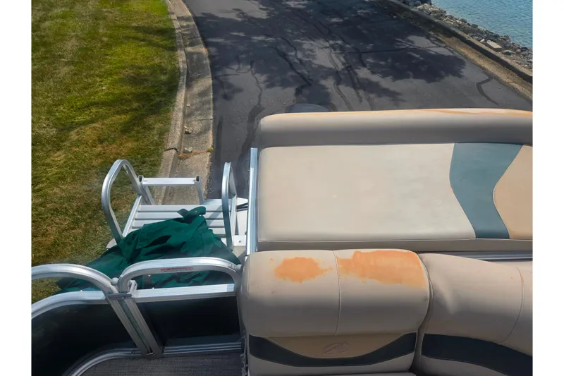 Slide: The Image of 2012 Avalon A Fish 16' boat with worn seating and ladder near water. - 15