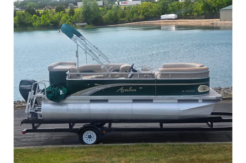 The Image of 2012 Avalon A Fish 16' pontoon boat on trailer by a serene lake. - 0