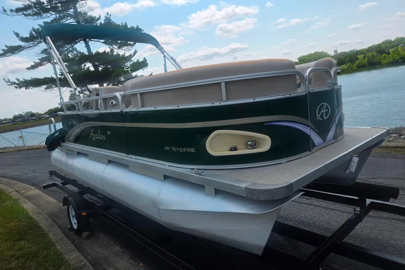 Slide: The Image of 2012 Avalon A Fish 16' pontoon boat on trailer by a lake. - 8