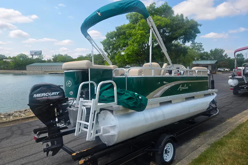 Slide: The Image of 2012 Avalon A Fish 16' pontoon boat with Mercury outboard motor on trailer by a lake. - 1