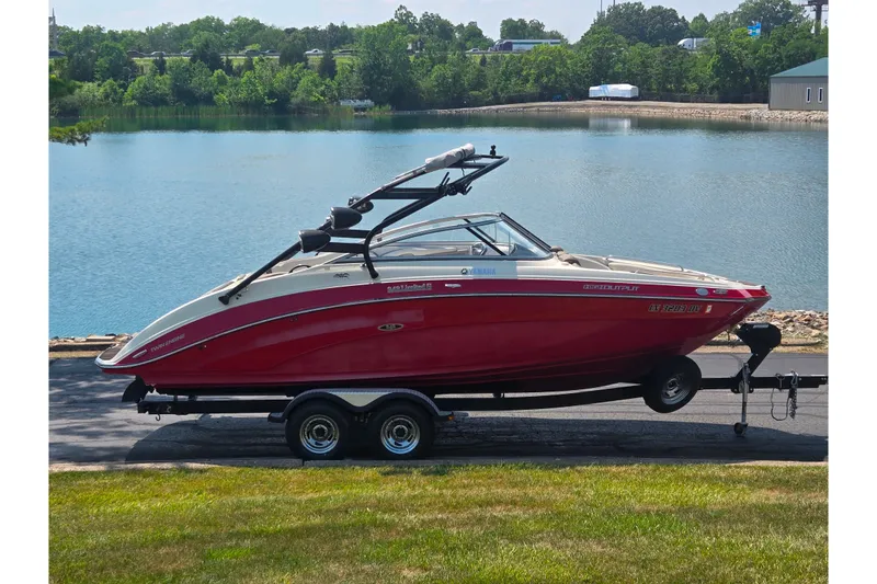 The Image of 2014 Yamaha Boats 242 Limited S on trailer by a scenic lake. - 0