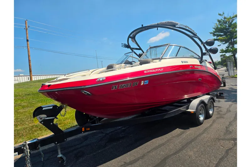 Slide: The Image of 2014 Yamaha Boats 242 Limited S in vibrant red on trailer, sunny day background. - 5