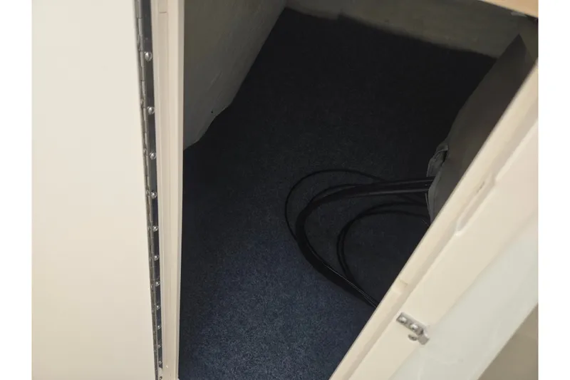 Slide: The Image of Storage compartment inside 2014 Yamaha Boats 242 Limited S, featuring carpeted flooring and cables. - 14