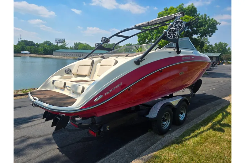 Slide: The Image of 2014 Yamaha Boats 242 Limited S on trailer by a lake, sunny day. - 1