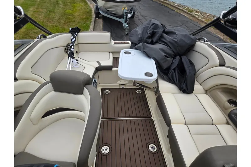 Slide: The Image of 2014 Yamaha Boats 242 Limited S interior with seating and table, docked by the water. - 22