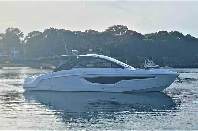 Slide: The Image of 2026 Cruisers Yachts 42 GLS OB on serene water with wooded shoreline backdrop. - 6