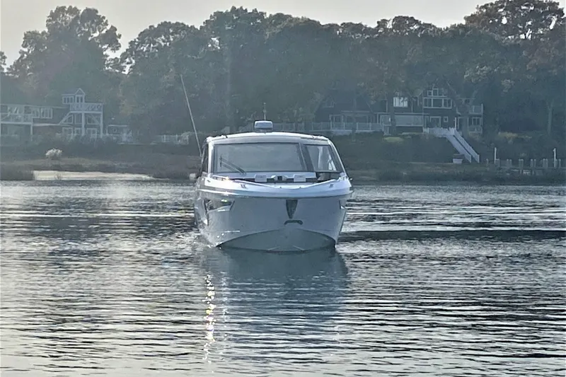 Slide: The Image of 2026 Cruisers Yachts 42 GLS OB on calm water, with scenic shoreline backdrop. - 4