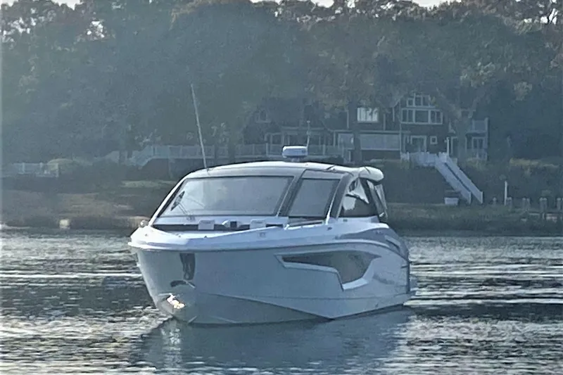 Slide: The Image of 2026 Cruisers Yachts 42 GLS OB on serene water with houses in the background. - 3