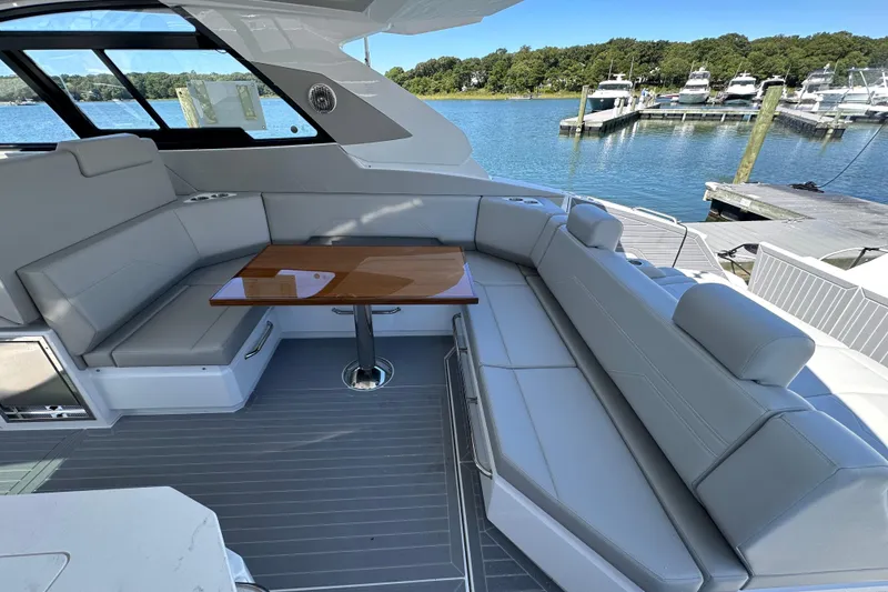 Slide: The Image of 2026 Cruisers Yachts 42 GLS OB interior with sleek seating and table, dockside view. - 11