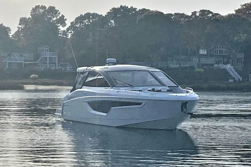 Slide: The Image of 2026 Cruisers Yachts 42 GLS OB on serene water with houses in the background. - 5