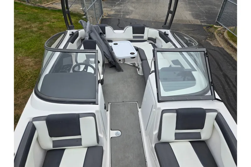 Slide: The Image of 2022 Yamaha Boats AR210 interior with seating and table, docked outdoors. - 19