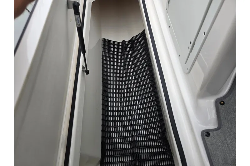 Slide: The Image of 2022 Yamaha AR210 boat storage compartment with black mat and hydraulic lift support. - 14