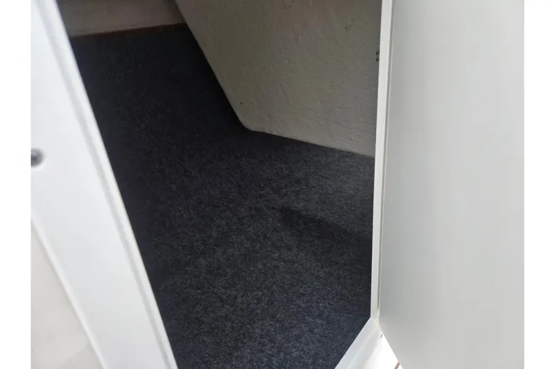 Slide: The Image of Interior storage compartment of 2022 Yamaha Boats AR210, featuring carpeted flooring. - 13
