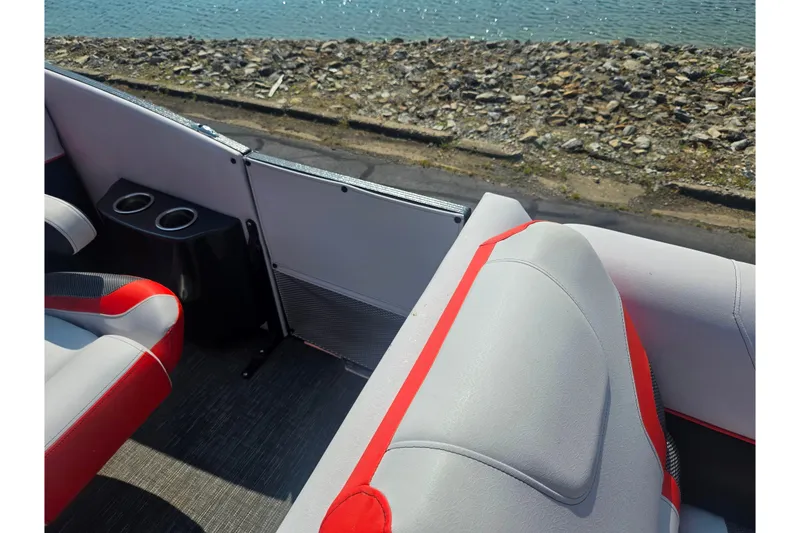 Slide: The Image of 2023 Crest Caribbean RS 230 boat interior with red and gray seating, cup holders, and water view. - 21