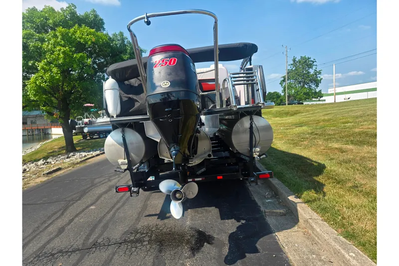 Slide: The Image of 2023 Crest Caribbean RS 230 pontoon boat with powerful outboard motor, parked on a sunny day. - 2
