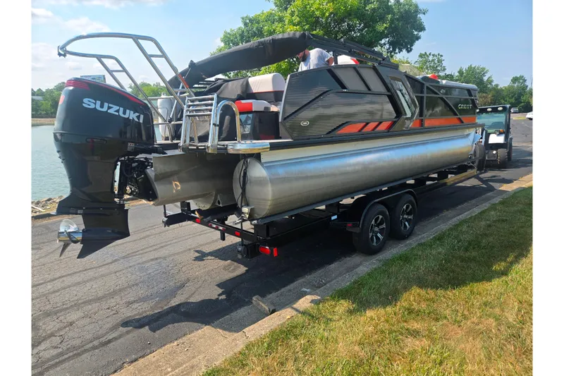 Slide: The Image of 2023 Crest Caribbean RS 230 pontoon boat with Suzuki engine on trailer by a lake. - 1