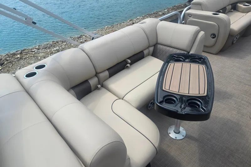 Slide: The Image of Luxurious seating and table on 2023 Sun Tracker SportFish 22 DLX pontoon boat by the water. - 22