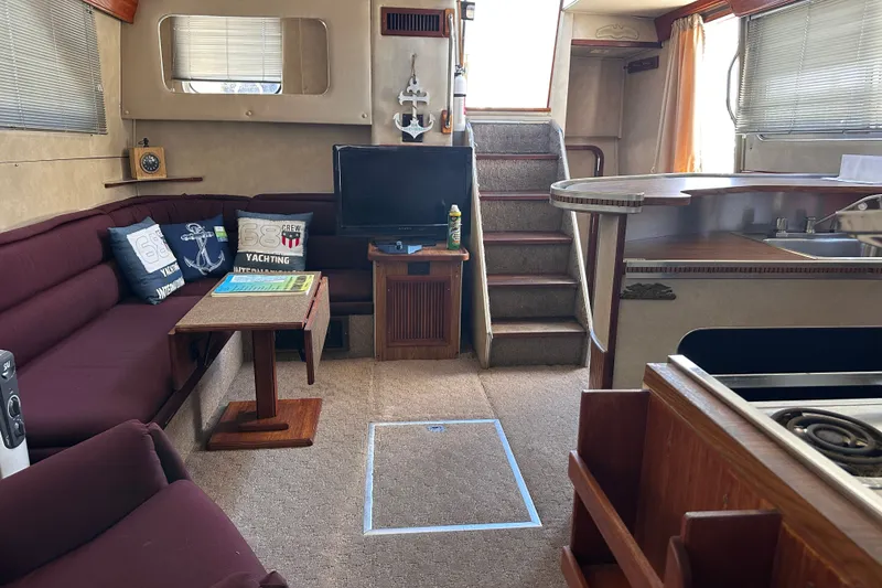 Slide: The Image of 1984 Chris-Craft 381 Catalina interior with cozy seating, TV, and nautical decor. - 28