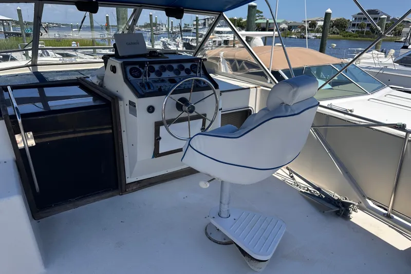 Slide: The Image of 1984 Chris-Craft 381 Catalina helm with steering wheel and captain's chair, docked at marina. - 11