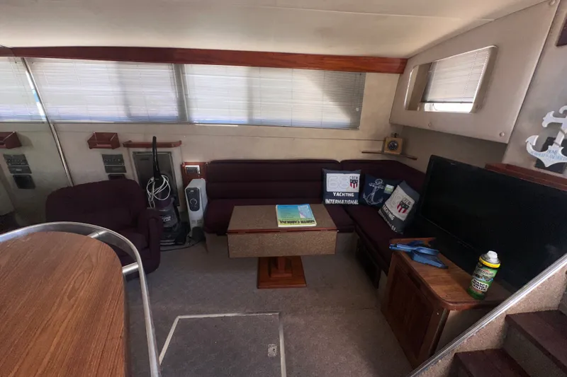 Slide: The Image of 1984 Chris-Craft 381 Catalina interior with seating, table, and TV in cozy cabin setting. - 16