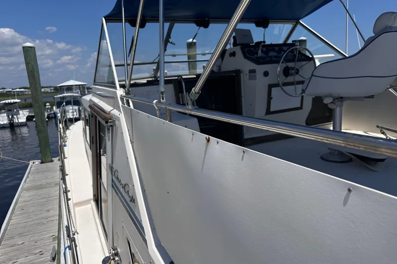 Slide: The Image of 1984 Chris-Craft 381 Catalina yacht docked, showcasing helm and seating area under blue sky. - 4