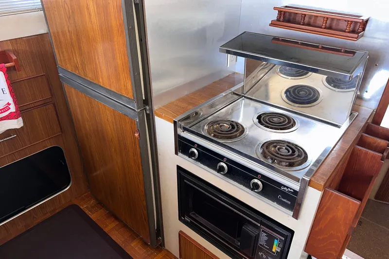 Slide: The Image of 1984 Chris-Craft 381 Catalina kitchen with stove, oven, and wooden cabinetry. - 17