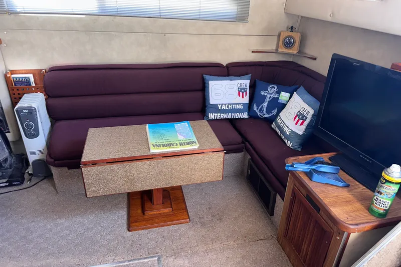 Slide: The Image of 1984 Chris-Craft 381 Catalina interior with maroon seating, nautical pillows, and a small table. - 15