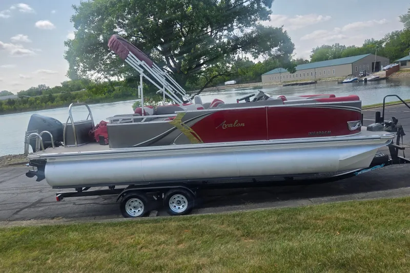 Slide: The Image of 2024 Avalon LSZ Cruise Bench pontoon boat on trailer by a lakeside. - 9