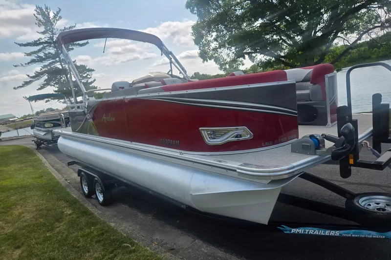 Slide: The Image of 2024 Avalon LSZ Cruise Bench pontoon boat on trailer by a lakeside. - 8