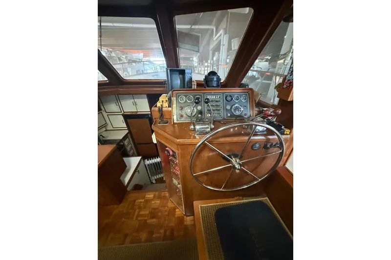 Slide: The Image of 1983 Ocean Alexander 43 Flush Aft Deck helm with classic wooden steering wheel and instrument panel. - 7