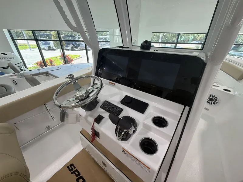Slide: The Image of The image shows the helm of a Sportsman Heritage 261 Center Console boat. It features a modern steering wheel, digital displays, and controls. The setting is bright and spacious. - 11