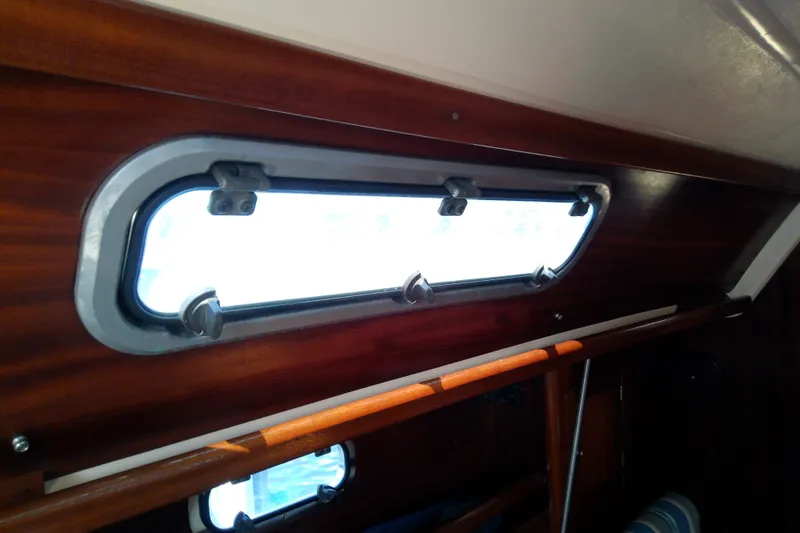 Slide: The Image of Interior view of a 2001 Bavaria Cruiser 37 yacht with wooden paneling and a porthole window. - 49