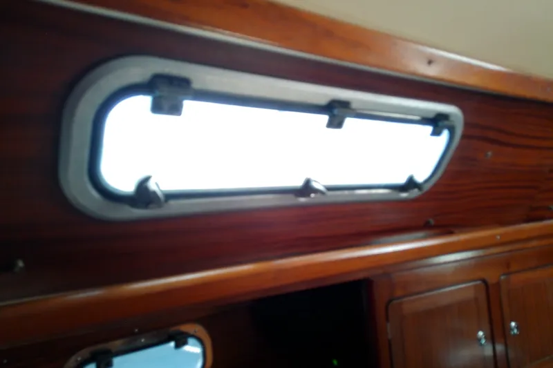Slide: The Image of Interior view of a 2001 Bavaria Cruiser 37 yacht, featuring a wooden cabin window. - 46