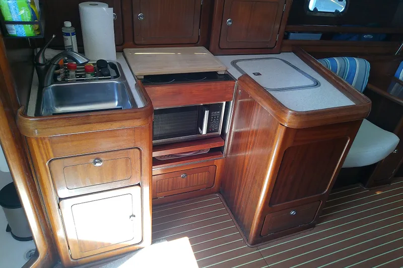 Slide: The Image of Wooden kitchen interior of a 2001 Bavaria Cruiser 37 yacht with sink and microwave. - 24