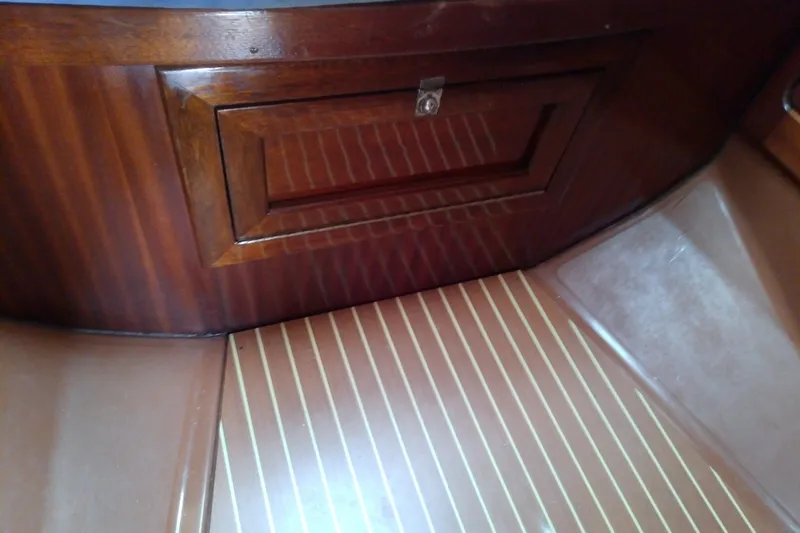 Slide: The Image of Wooden interior of a 2001 Bavaria Cruiser 37 yacht, featuring a polished cabinet and striped flooring. - 45