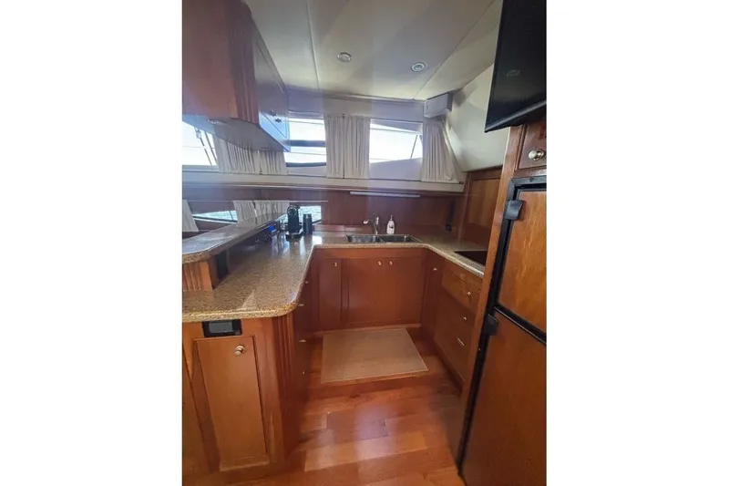 Slide: The Image of Luxurious 2004 Cruisers Yachts 455 Express Motoryacht kitchen with wood cabinetry and modern appliances. - 30