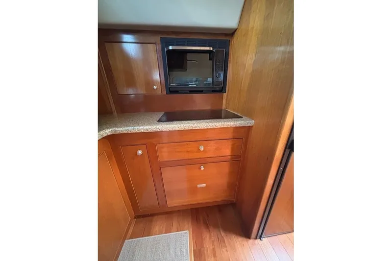 Slide: The Image of 2004 Cruisers Yachts 455 Express Motoryacht kitchen with wood cabinetry and built-in microwave. - 25